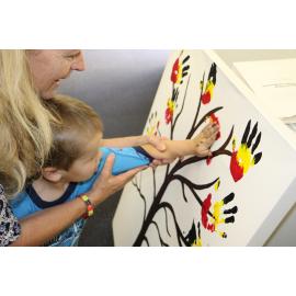 Tracy Willet (Museum curator) assisting child with placing hand on painting