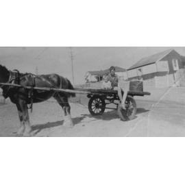 Roy Thompson on Malcolm Street on cart in front of shop