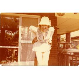 Rae at front of house in white hat