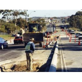 Worker shovelling sand during island installation on unknown dual carriage way 