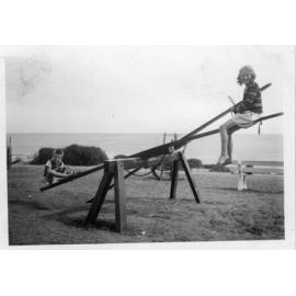 Children enjoying the play equipment on the grassed area in Watermans Bay C1950