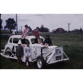 Arbuckle children sitting on stock car 47 with Gwelup School in background