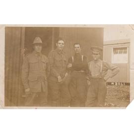 World War One era photograph of two men in military uniform with two men out of uniform